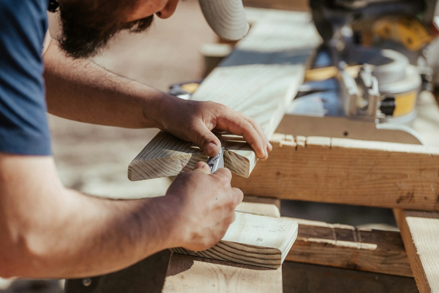 Hands working timber with tools